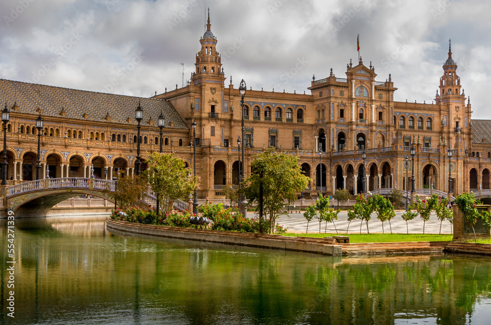 Amazing Plaza de Espana in Seville, Spain. Water reflection of the palace buildings on the adjacent canal. One of major Spanish tourist attractions. Regionalism architecture.