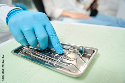 Experienced dentist selecting tool for patient examination