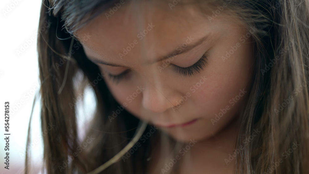 Sad little girl child with eyes closed looking down pensive female child suffering from emotional pain Sad little girl child with eyes closed looking down pensive female child suffering from emotional pain