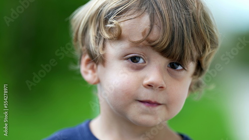 Adorable child portrait smiling at camera little boy face closeup smiles outside at park