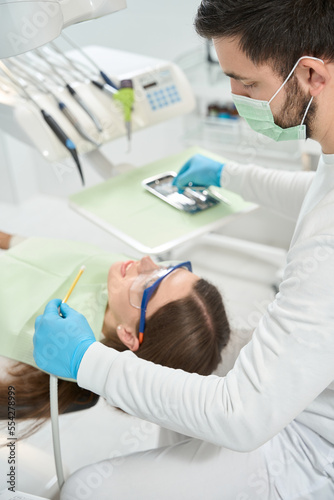 Professional stomatologist preparing to examine female client