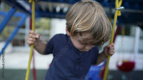 Child standing on playground swing carefree kid playing