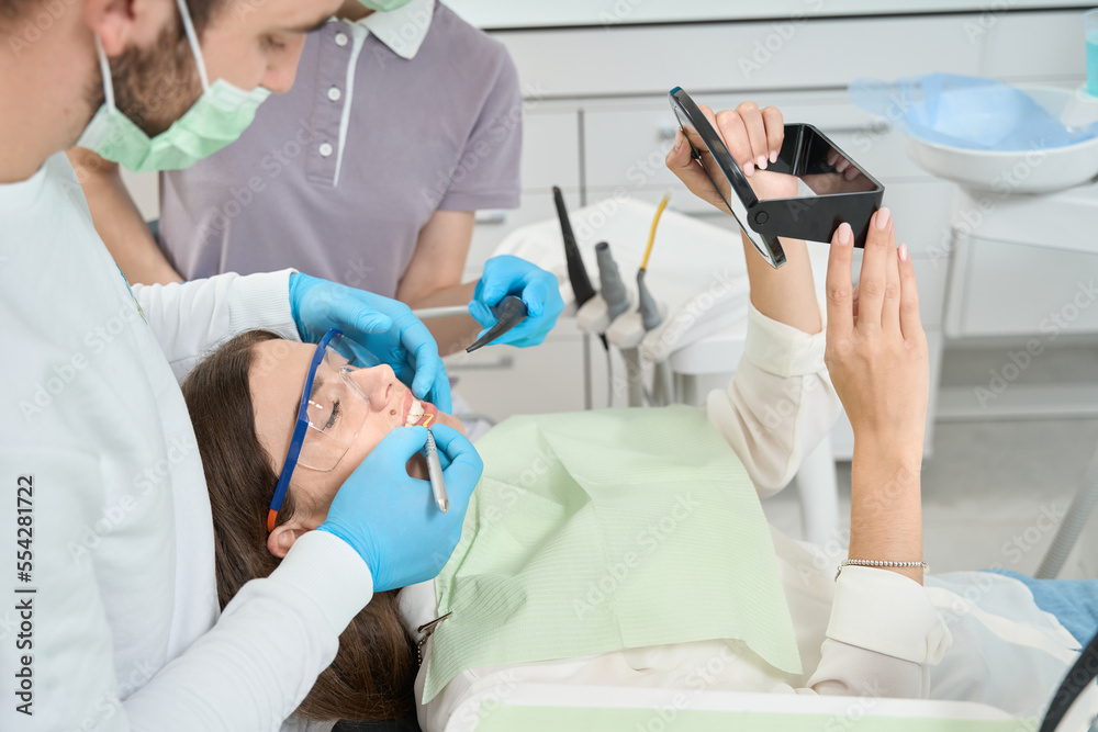 Dentist conducting interdental cleaning on young woman Dentist conducting interdental cleaning on young woman