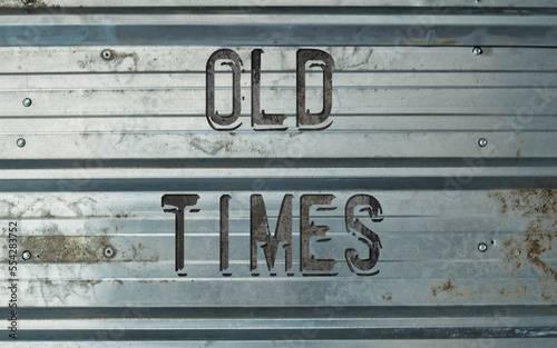 Old rustic metal wall with letters saying 'old times'. Weathered metal surface with letters on top. Old-time, vintage, nostalgic abstract symbol image.  