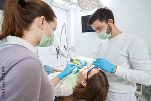 Experienced dentist treating caries in female client