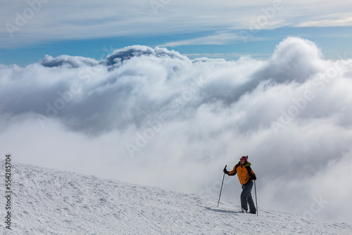Epic scene of woman at the summit of mountain as symbol of life success. Silhouette of man tourist standing at top. Incredible panoramic view of snow capped mountain ridge