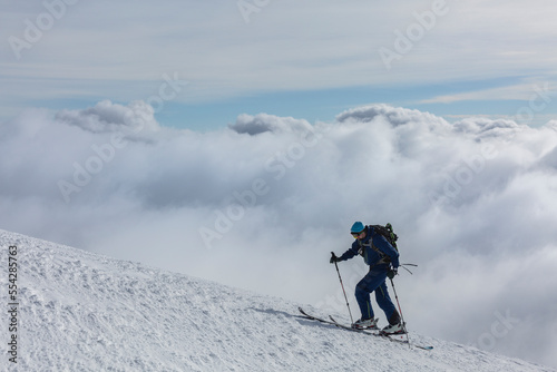 brave hiker on the edge of mountain with natural sky and clouds background. Cloudy cover over mountains