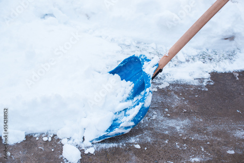 Winter problems concept . Woman digging snow with shovel at yard. Lady standing with blue shovel and cleaning snow .Winter routine concept