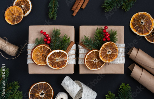 Craft gift boxes with dried oranges, spruce branches and berries
