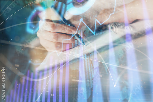 Financial forex graph displayed on hands taking notes background. Concept of research. Double exposure