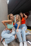 Beautiful girls in fashion bright urban denim clothes with a top, jeans and white sneakers in the subway