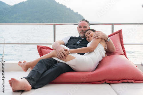 happy senior couple in love on the side of sail on yacht deck floating in sea and enjoy. Love relationship and travel elderly people lifestyle concept