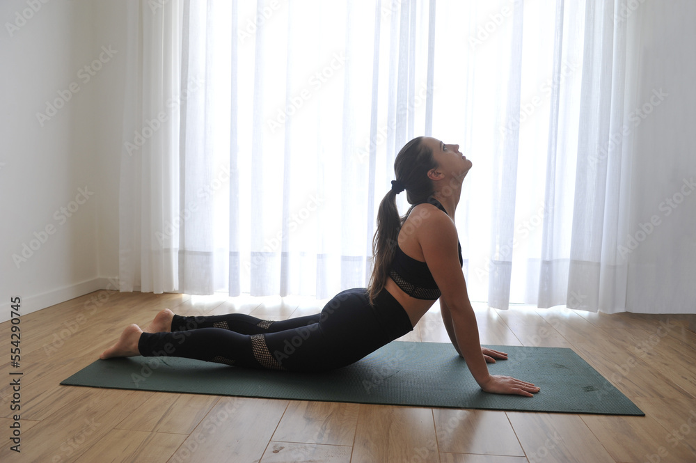 mulher linda fazendo alongamentos exercidios de yoga e meditação em casa 