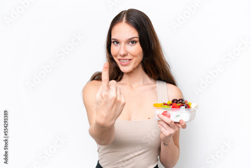 Young caucasian woman holding a bowl of fruit isolated on white background doing coming gesture