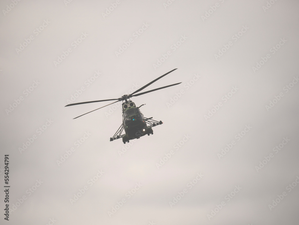Fototapeta premium Military helicopter flying against a cloudy sky. Airshow demonstration.