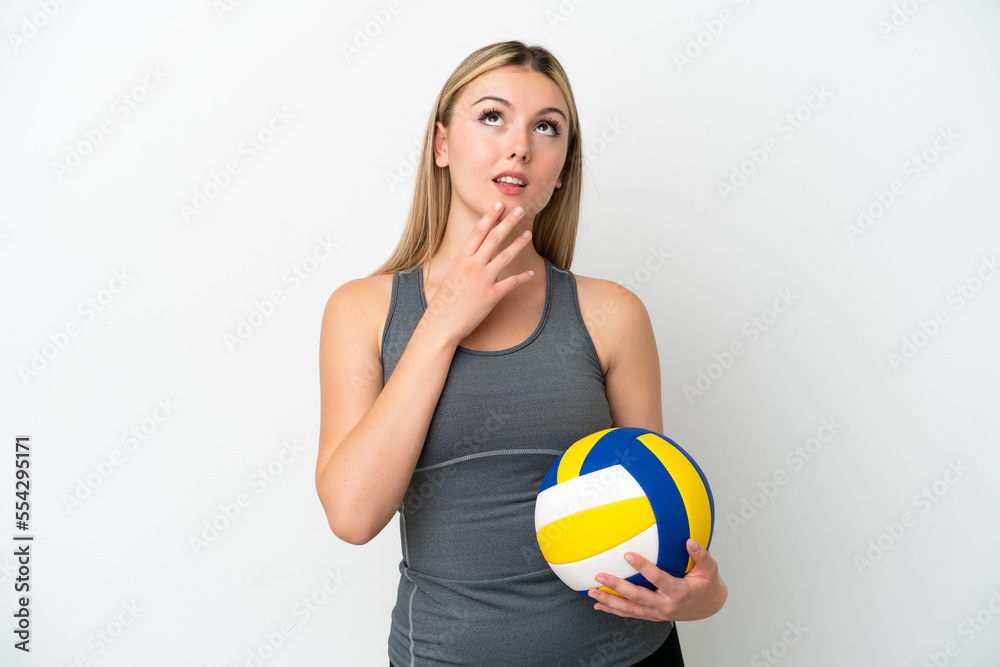 Young caucasian woman playing volleyball isolated on white background looking up while smiling