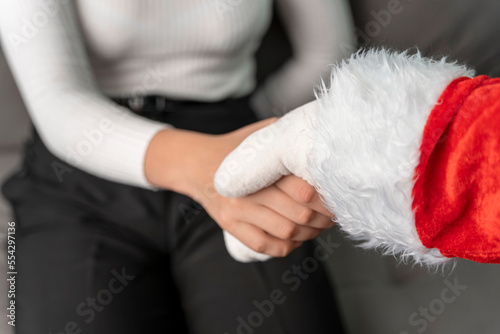 Santa shakes hands with a girl congratulating her on Christmas