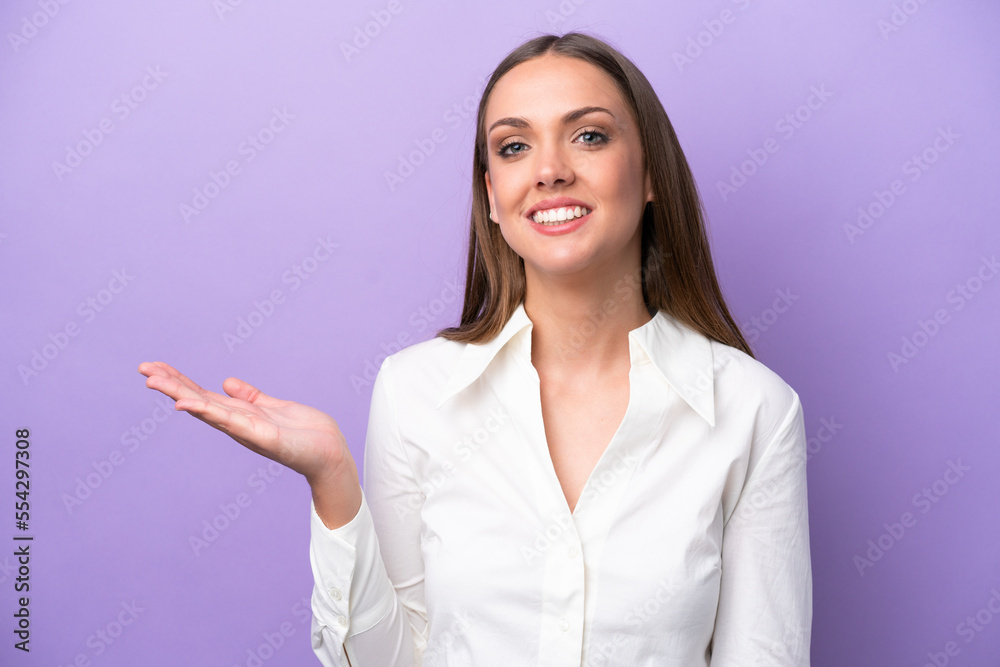 Young caucasian woman isolated on purple background holding copyspace imaginary on the palm to insert an ad Young caucasian woman isolated on purple background holding copyspace imaginary on the palm to insert an ad