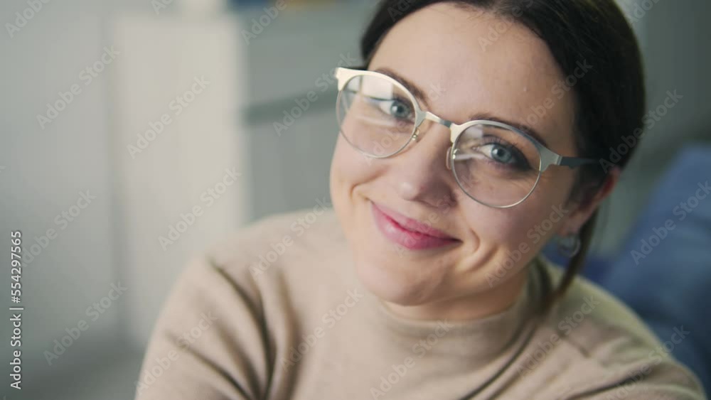 Beautiful brunette woman in big eyeglasses looking at camera and smiling, don't hesitate to talk about her women's health, receiving decent medical care, private clinic Beautiful brunette woman in big eyeglasses looking at camera and smiling, don't hesitate to talk about her women's health, receiving decent medical care, private clinic