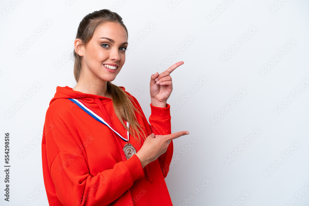 Young caucasian woman with medals isolated on white background pointing finger to the side and presenting a product Young caucasian woman with medals isolated on white background pointing finger to the side and presenting a product
