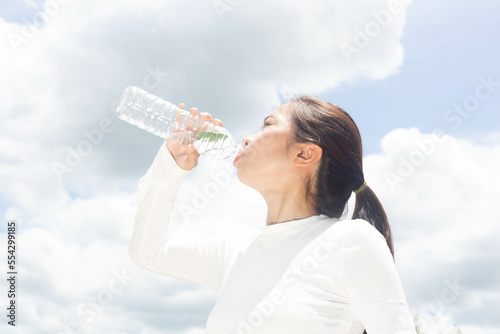 Fotografie Girl drinking water to quench thirst on a hot summer day, heat exhaustion, heat stroke