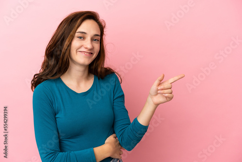 Young caucasian woman isolated on pink background pointing finger to the side © luismolinero