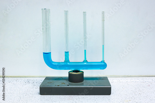 Glass equipment where several different connected tubes are filled with a blue liquid, demonstrating capillary action. Used in physics class. photo