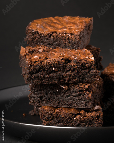 Stack of rich chocolate brownies on a dark plate.