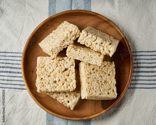 Rice Krispie treats on a ceramic plate over a striped cloth.