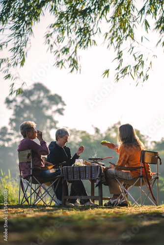 woman family having fun with food of picnic camp in the nature morning, summer travel vacation lifestyle of mother and girl at adventure forest park landscape in holiday, outdoors activity breakfast