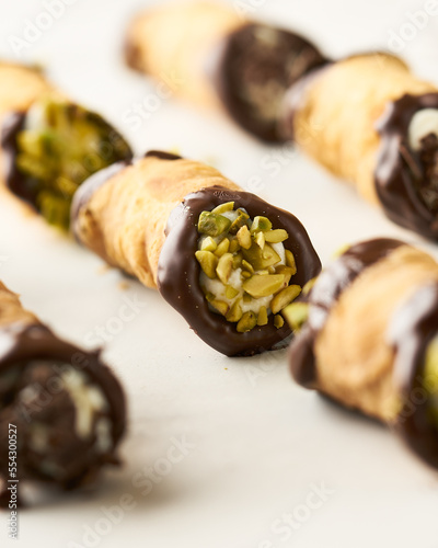 A series of cannoli with pistachio pieces, dipped in chocolate, perfect for dessert-themed stock photos.