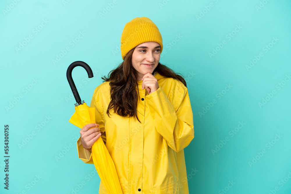 Young caucasian man holding an umbrella isolated on blue background looking to the side and smiling Young caucasian man holding an umbrella isolated on blue background looking to the side and smiling