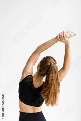 Exercises to warm up the back, the woman raised her hands up, view from the back.