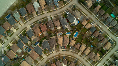 An aerial drone shot of roads, houses, backyards & swimming pools in the suburbs