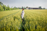 lauphing woman with short hair in white dress walking in wheat field