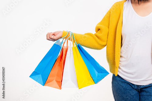 Happy woman hand she wears yellow shirt holding shopping bags multicolor, young female hold many packets within arms isolated on white background, Black Friday sale concept