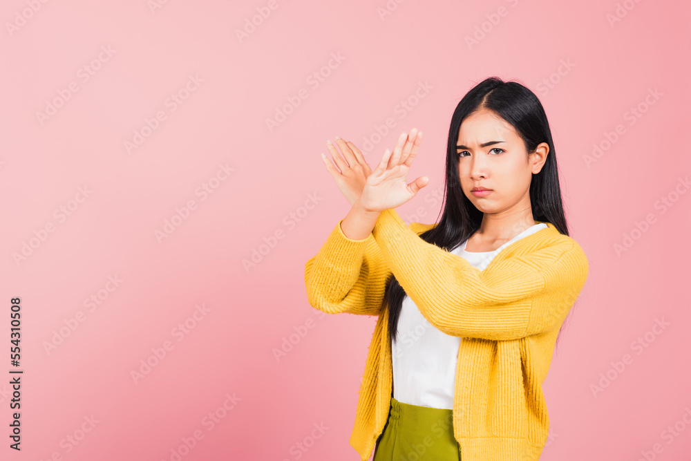 Portrait Asian beautiful young woman unhappy or confident standing wear holding two cross arms say no X sign, studio shot isolated pink background, Thai female pose reject gesture with copy space Portrait Asian beautiful young woman unhappy or confident standing wear holding two cross arms say no X sign, studio shot isolated pink background, Thai female pose reject gesture with copy space