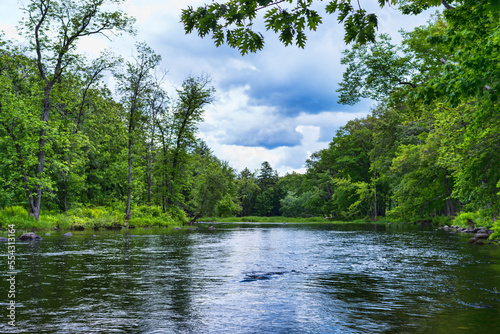 Shallow spring river flowing into the distance with vibrant green riverbanks. photo
