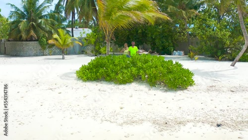 Couple on a tropical beach with blue water and palm trees and white sand on local island Bodufolhudhoo in Maldives. Aerial drone view. photo