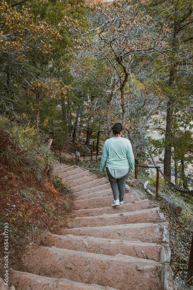 woman walking on a trail in winter with frozen over path on a popular hike section of Zion national park in utah united states of america.