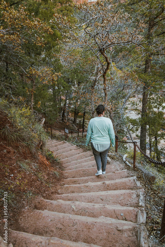 woman walking on a trail in winter with frozen over path on a popular hike section of Zion national park in utah united states of america.