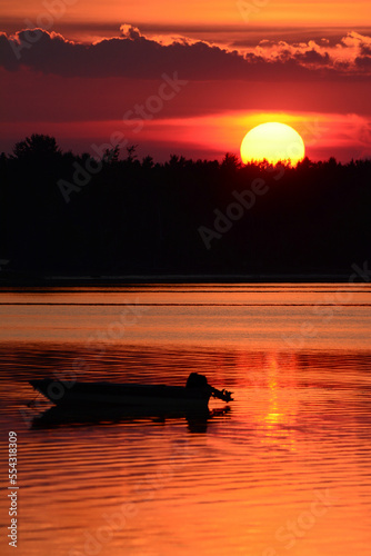 A silhouetted boat at sunset at Cote a Fabien.; Cote a Fabien, Kouchibouguac National Park, Kouchibouguac, New Brunswick, Canada. photo