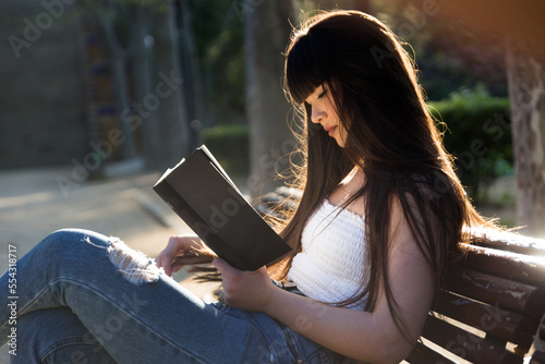 Young asian woman with a fringe reading a black book in the streets og Barcelona with natural sun light