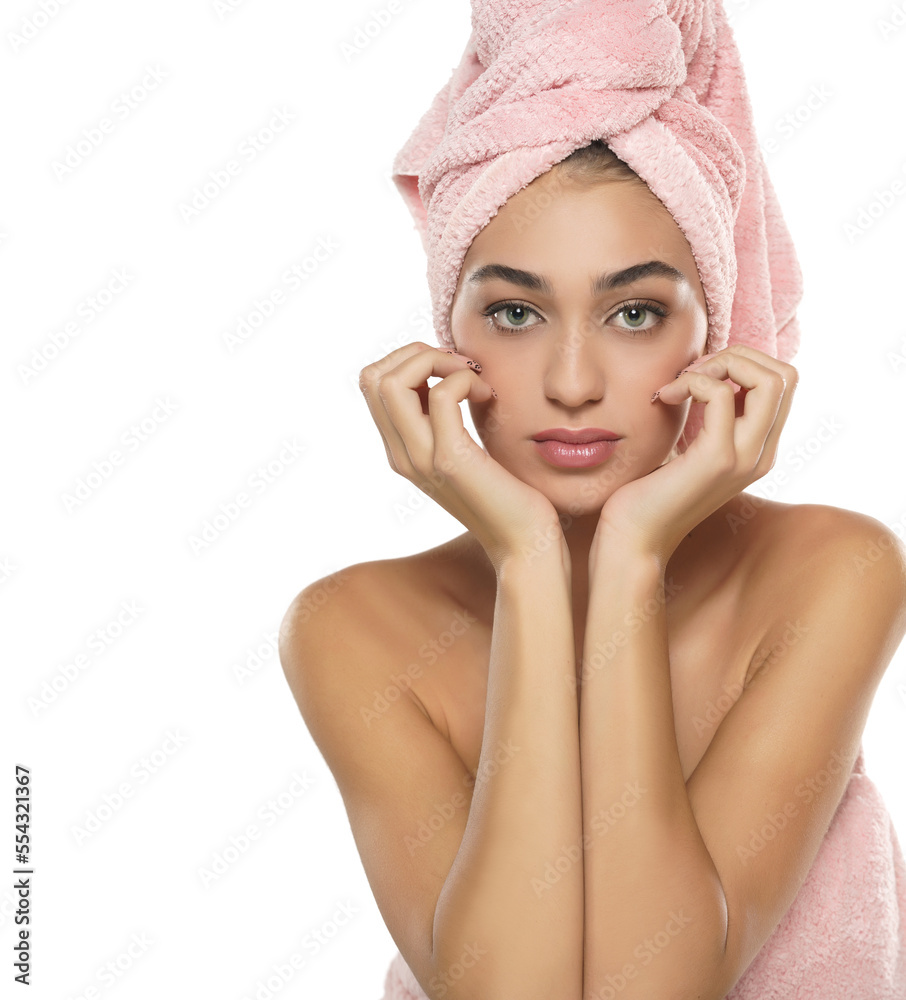 A pretty young woman with towel on her head posing on a white background A pretty young woman with towel on her head posing on a white background