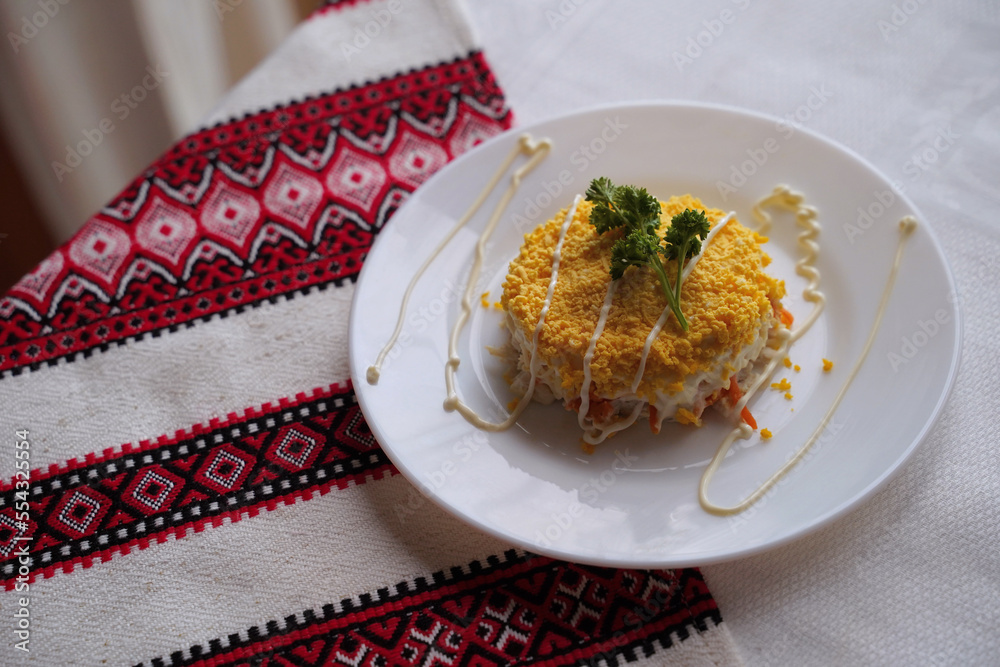 Homemade mimosa salad. Traditional Ukrainian food on the table with embroidered tablecloth.