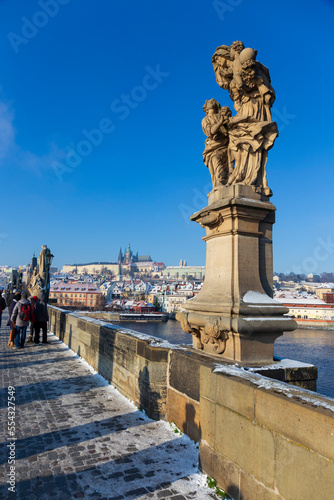Sunny snowy Prague Lesser Town with gothic Castle from Charles Bridge and its baroque Statues, Czech republic