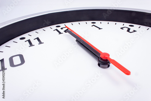 Midnight. Black and white office clock with a red pointer on a gray background.