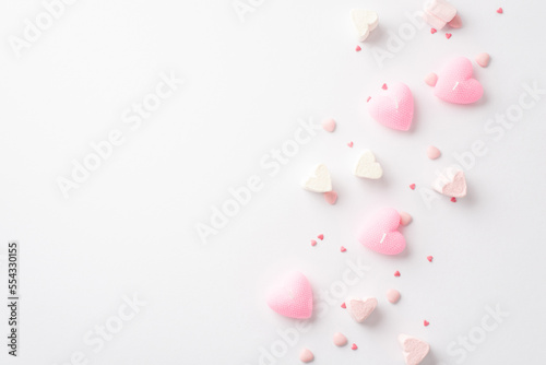 Valentine's Day concept. Top view photo of heart shaped candles marshmallow and sprinkles on isolated white background with empty space