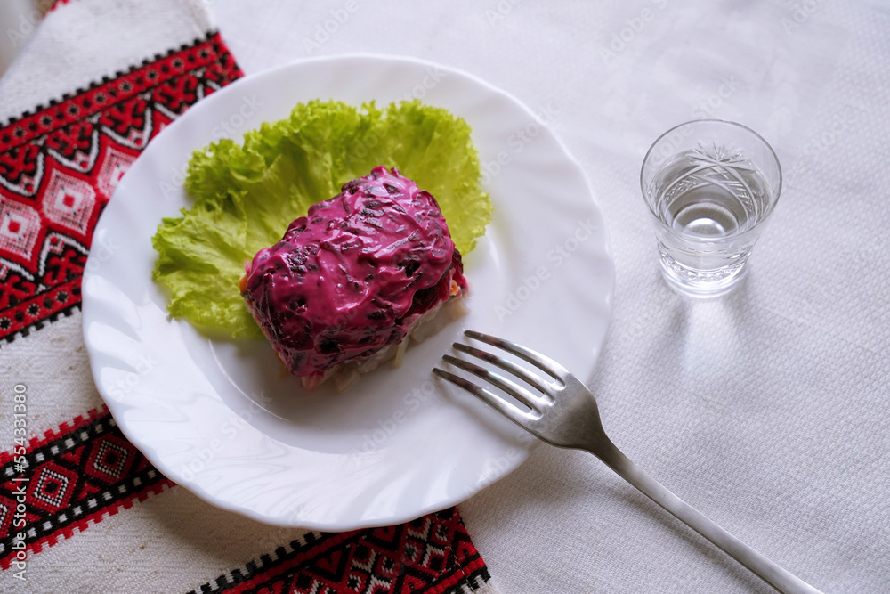 Dressed herring salad with a glass of horilka. Traditional Ukrainian food.