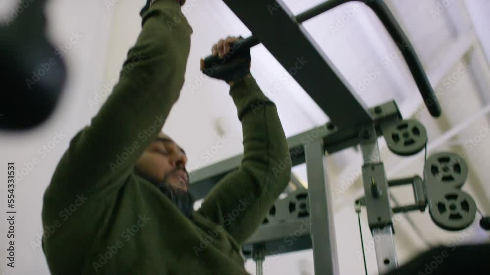 Healthy young man doing core exercises as he hangs from bars in the gym Healthy young man doing core exercises as he hangs from bars in the gym